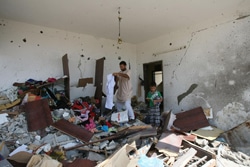 停戦中に家に帰り、破壊された家のがれきの中から荷物を探す親子。