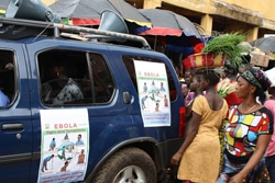 車に貼られたエボラに関するポスターを読む住民。