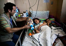 ガザ市にあるシファ病院で、心のケアを行うスタッフから人形を受け取る少女。