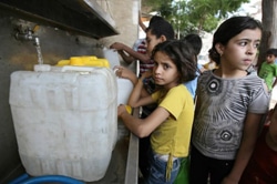 水の供給所で、列になって水を汲む子どもたち。（ガザ）