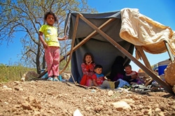 国内避難民キャンプの付近で、仮のテントの下で休息を取る母親と4人の子どもたち。暴力から逃れるため、家族で避難してきた。