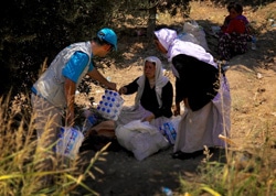 シリアの国境まで逃れてきたヤズディ教徒の女性たちに、水を提供するユニセフ・スタッフ。（イラク）