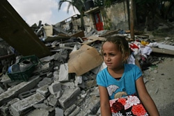 停戦中に空爆で破壊された自宅を訪れ、必要な荷物をがれきの中から探す女の子。（ガザ）