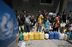 ユニセフはガザの子どもたちや家族に安全な飲み水を提供。水の供給所で水を汲むために列に並ぶ子どもたち。（ガザ）