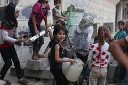 シリア・ダマスカス郊外で水を汲むために給水所に集まる子どもたち。