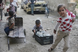 水の入った容器を家まで運ぶ子どもたち。（シリア）