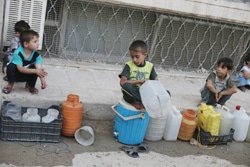 水の容器を持って順番を待つ子どもたち。（シリア）