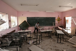 戦闘の被害を受けた教室の被害状況の調査や片づけを行う男性。(ガザ)
