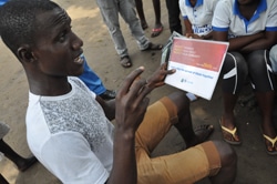 エボラ啓発用冊子を手にするニュー・クル・タウンの住民。（リベリア）