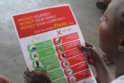エボラの啓発用ポスターを手にする女の子。（リベリア）