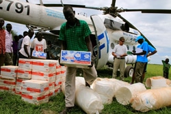 上ナイル州のKiech Kuonに届けられた、すぐに口にできる栄養補助食をヘリコプターから運び出すスタッフ。（南スーダン）