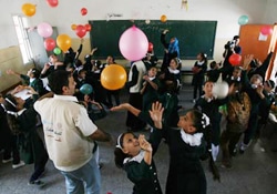 ガザの学校で風船を使って子どもたちとゲームをするカウンセラー。レクレーション活動を通じて、子どもたちが徐々に学習へ戻れるようにする取り組みの一環。
