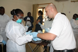 米国疾病対策予防センターのベン・レヴィー氏が、感染防止のため、ゴム手袋を二重にして着用するよう指導。（シエラレオネ）