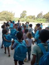 通学かばんを背負って家族のもとに帰る、スポーツ・シティー避難所の子どもたち。（シリア）
