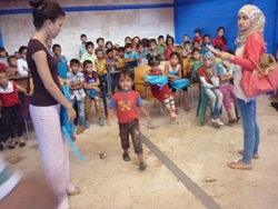通学かばんを先生から受け取る2年生の生徒たち。（シリア）