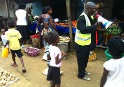市場でエボラの予防法を伝える保健員。（ナイジェリア）