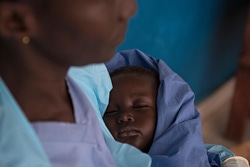エボラの感染が疑われる人たちが身を寄せるセンターで、抱かれて眠る1歳の赤ちゃん。エボラの症状は出ていないものの、両親をエボラで失い、面倒をみることができる親せきを探している。（シエラレオネ）