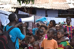 町を訪れ、エボラの予防法を子どもたちに説明するスタッフ。（ギニア）
