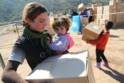 クルド地方北部のドホーク州で、妹を抱きながら支援物資の衣類を受け取った少女。（イラク）