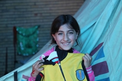 クルド地方北部のドホーク州で、支援物資の衣類を受け取り、笑顔を見せる少女。（イラク）