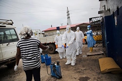 エボラ患者の遺体の搬送を担う保健員たち。防護服を身につけ、消毒を行う様子。