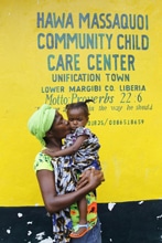 両親がエボラに感染して治療センターに搬送された後、兄弟と一緒に一時ケアセンターに連れてこられた1歳半の女の子とセンターのスタッフ。（リベリア）