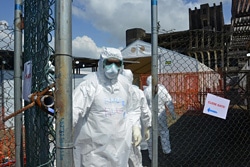 防護服で身を包み、新しく設置されたエボラ治療ユニットから外に出る保健員。（リベリア）