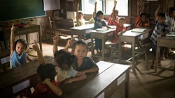 「幼稚園に行った人は何人ぐらいいるかな？」と聞かれ、手を挙げる小学校に通う児童たち。