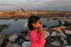 スマトラ沖地震・津波の災害後、バンダ・アチェ郊外の自宅があったあたりで立ち尽くす女の子。鼻を覆わなければならないほど、臭気が漂っていた(2005年、インドネシア) 