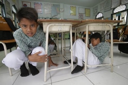 避難訓練で机の下に隠れるバンダ・アチェの小学校の児童たち。