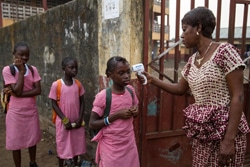 ギニアのコナクリにある小学校で学校が再開。登校する生徒たちに非接触式体温計を使って体温検査を行う様子。