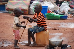 避難所で、幼い男の子にすぐ口にできる栄養治療食を食べさせてあげる少年。（南スーダン）
