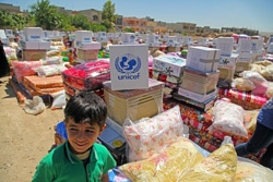 イラクに届けられたユニセフの支援物資の前で笑顔を見せる男の子。（イラク）