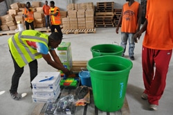 学校再開に向け、温度計や手洗い用のバケツ、消毒液、手袋などの支援物資を用意するスタッフ。