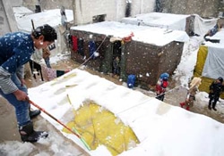 レバノンのベッカー高原で、テントの雪下ろしをするシリア難民の男の子。