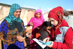 タブレット端末にシリア難民の家族の情報を入力するスタッフ。