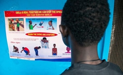 エボラの症状などがのっているポスターを読む少年。（リベリア）