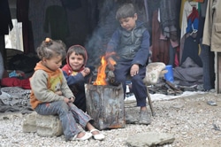 暖を取るシリアの子どもたち。