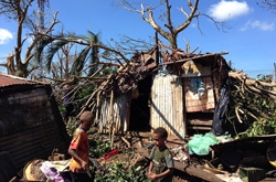 バヌアツのサイクロンで破壊された家の前で作業をする子どもたち。