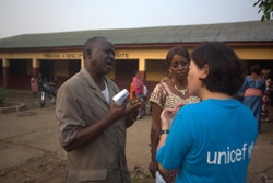 非接触型の体温計を持つ男性と話す青木さん。