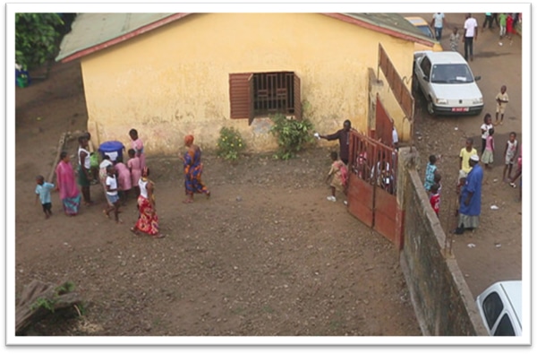ギニアで再開された学校の様子（入口付近に立つ青木さん）