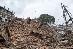 首都カトマンズの破壊された建物の瓦礫の上を歩く人々。