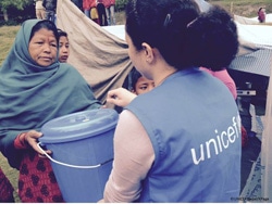 被災した家族に水と衛生の支援物資を届けるユニセフスタッフ