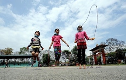ユニセフの「子どもにやさしい空間」に集まり、屋外で縄跳びをする女の子たち