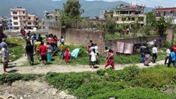 大規模な余震後、カトマンズの人々が屋外や道に集まる様子。