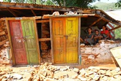 地震で崩壊した教室の瓦礫の山の上に座るサンジョグくんとシャンティちゃん、サミクシャヤさん。