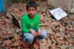 瓦礫の中に座り込む14歳の少年。