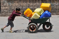 サナアで、プラスチック製の給水タンクを積んだ台車を押して、水を汲みに行く男の子