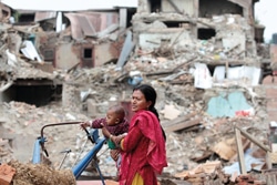 被災したバクタプルの町を歩く親子。