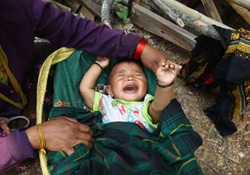 7カ月の赤ちゃんの面倒をみるおばあさんは、4月25日の地震で義理の娘を失った。地震以降、赤ちゃんがなかなか泣き止まなくなったと語る。